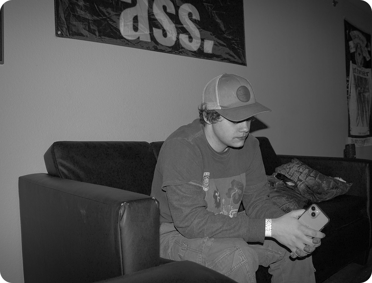 black and white image of a college student sitting on the couch with a phone in his hand, contemplating the night
