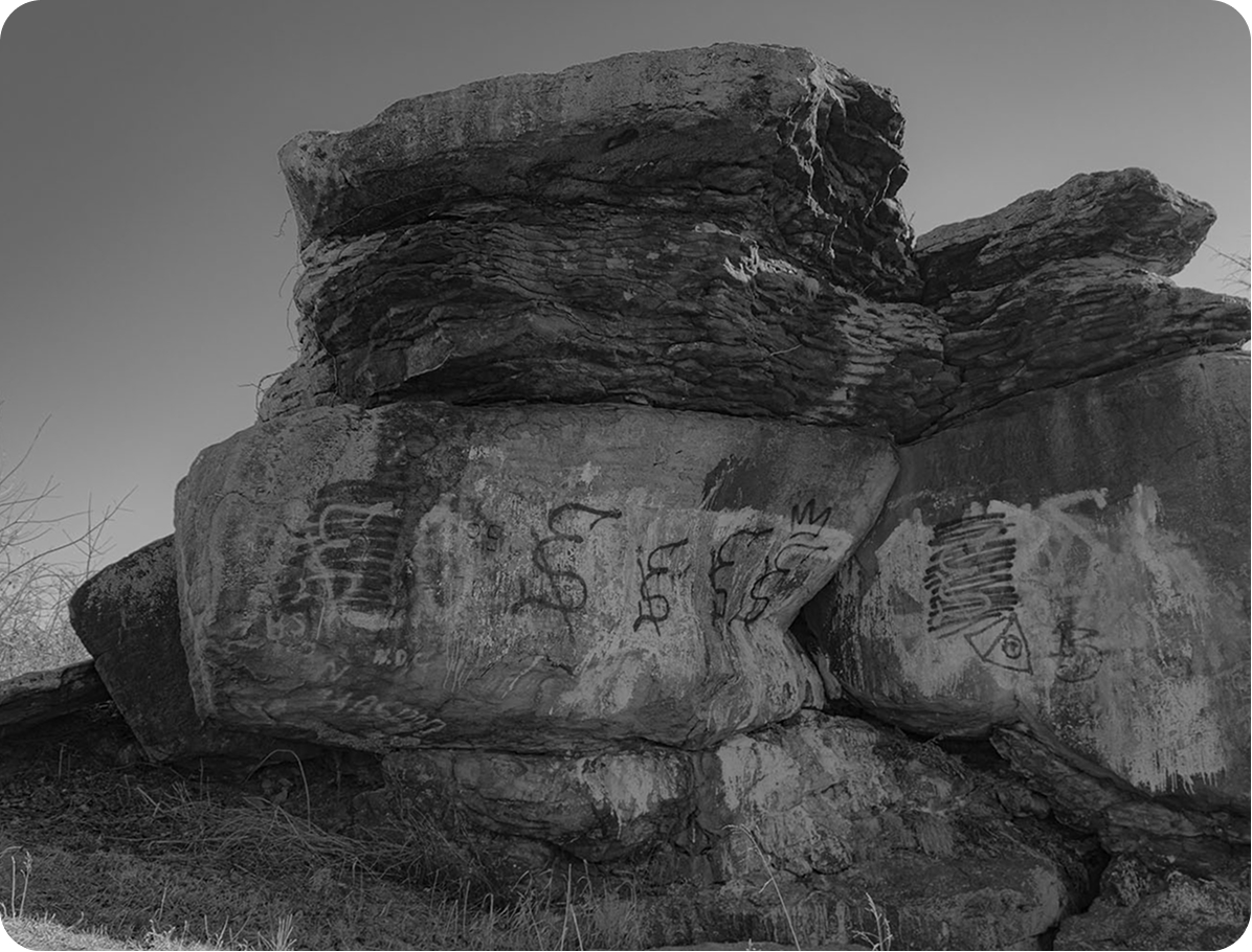 black and white image of a pile of boulders containing graffiti
