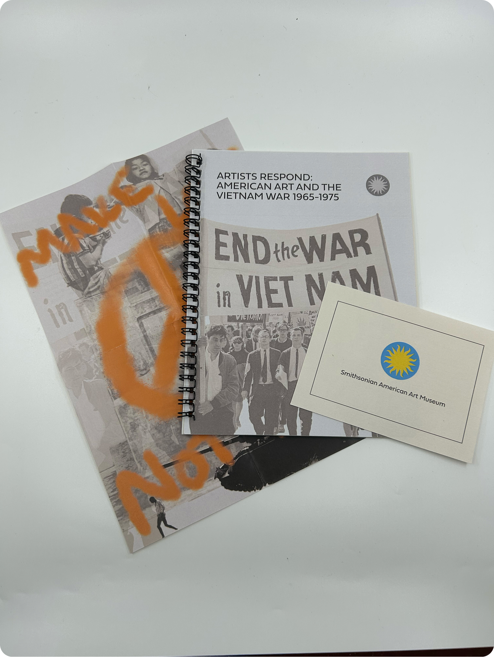 A poster, catalog book, and donor card laid out in a spread